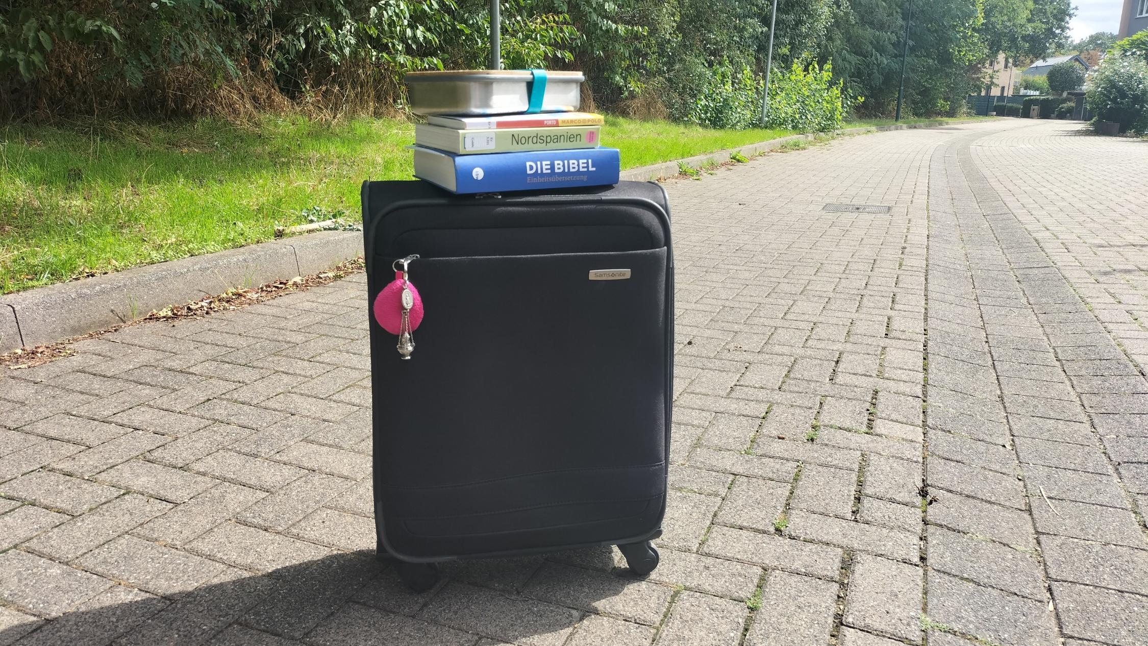 Koffer, Bibel, Reiseführer und Brotdose stehen bereit